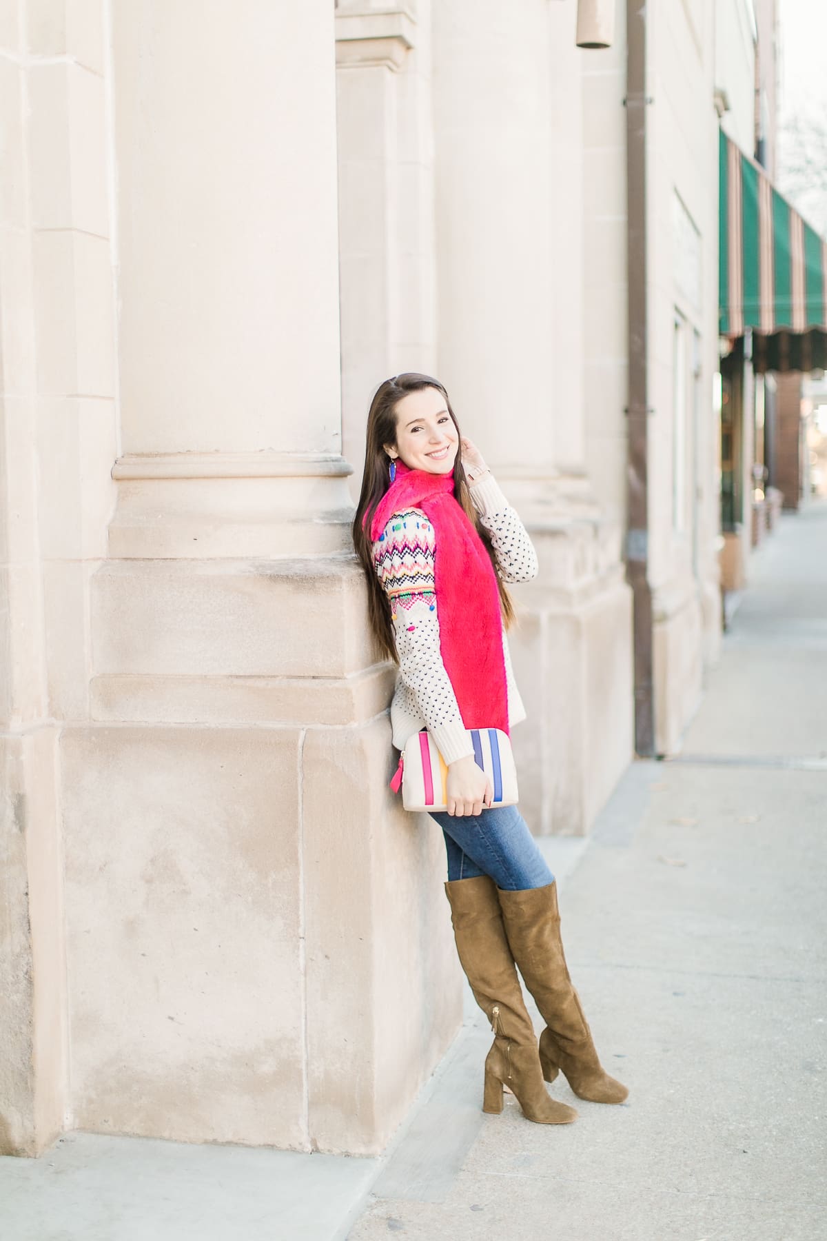 Colorful Christmas sweater ideas from Talbots, featuring their Carnival Fair Isle Sweater, Pink Faux Fur Pull Through Scarf, and Canvas Stripe Makeup Pouch styled with AG the Legging ankle jeans, taupe Free People Liberty boots, and cognac Kendra Scott Skylar earrings by southern fashion blogger Stephanie Ziajka from Diary of a Debutante